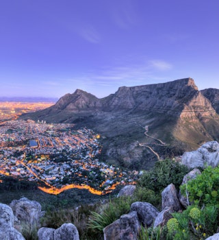 Looking down over Cape Town from the top of Lions Head peak, this view shows table mountain warmly lit in afterglow of sunset. The streets of the city are alight with the headlights of cars © Quality Master / Shutterstock