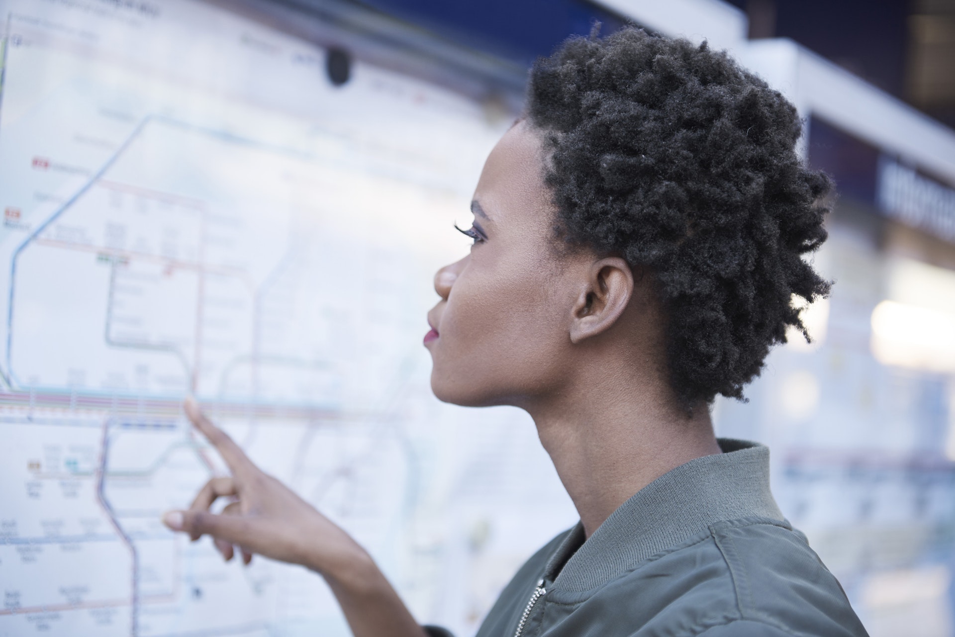A young woman is looking at a public transport map on the wall of a station in Munich