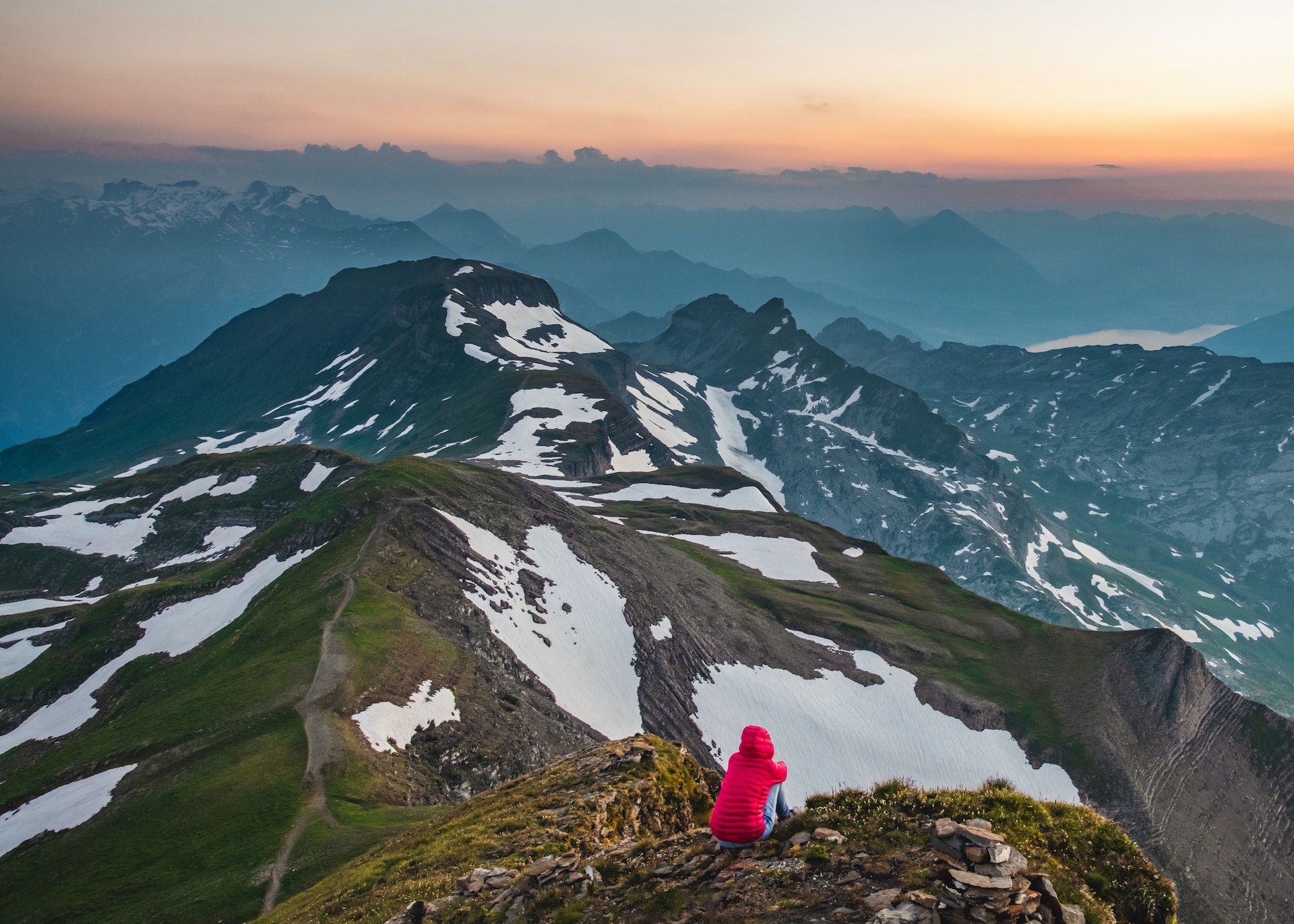 Lone hiker woman watches the sunset over Lake Brienz in Switzerland from the Faulhorn