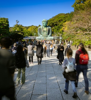 Kamakura, Kanagawa Prefecture, Japan - October 23, 2021: Tourists walk around the Great Buddha, or Kamakura Daibutsu, the 43 foot tall and 103 ton statue which was completed in 1252.