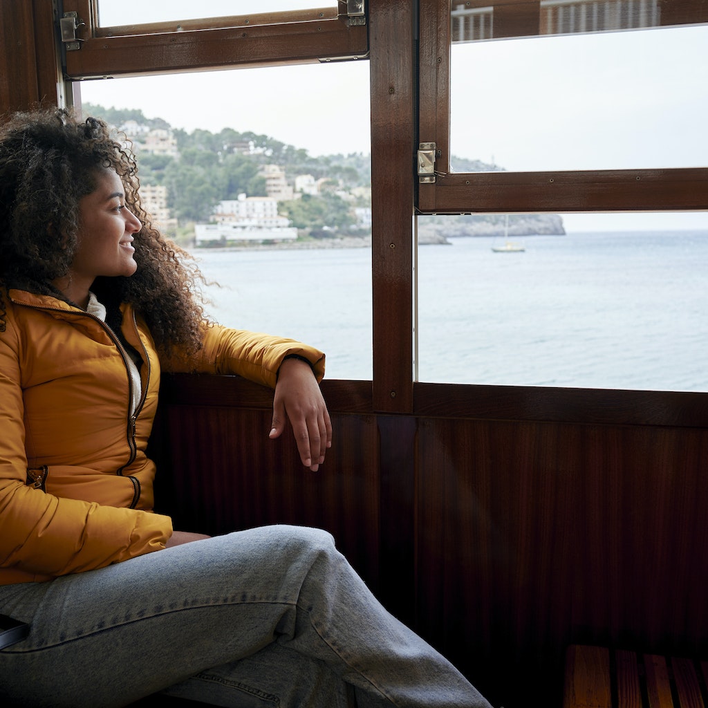 Woman in train looking out the window at the sea
1395582553
A woman smiling and looking out the window at the sea view in Spain