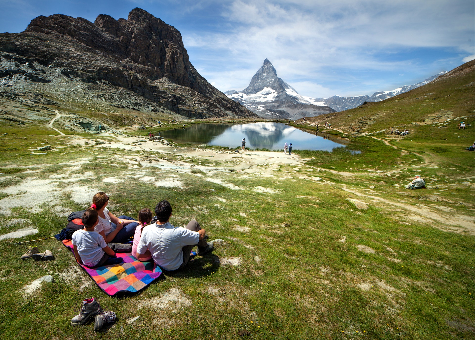 A family of four is having fun relaxing on the lawn in front of the Matterhorn.