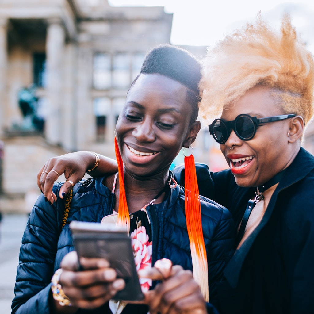 Happy friends using mobile phone in Berlin City.
957556544
Two black women laughing together while looking at a phone in Berlin
