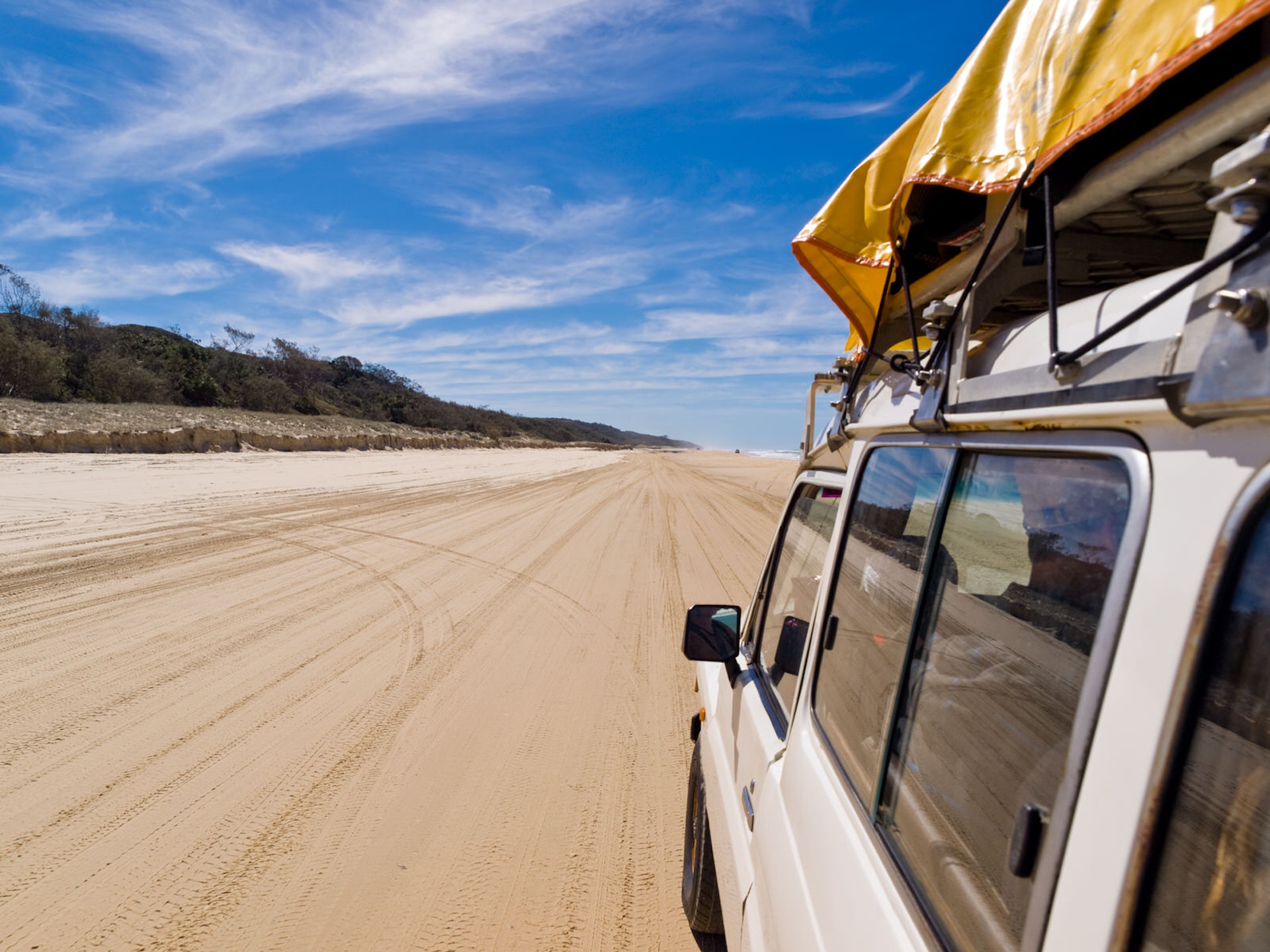 Car driving along a sandy beach on Fraser Island, Queensland, Australia