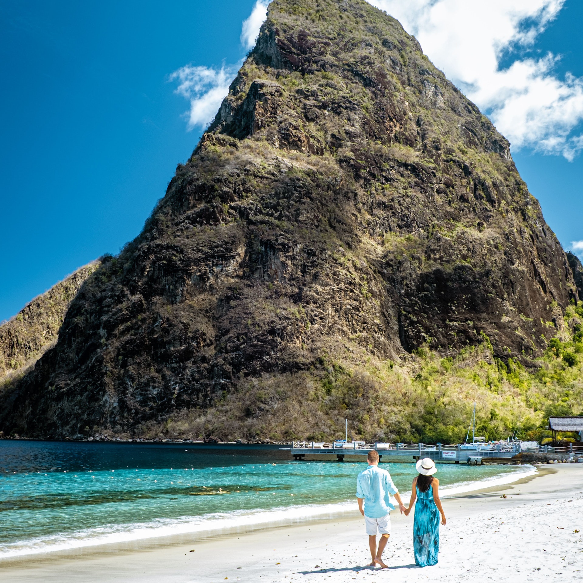 A couple walks on a beach in front of Gros Piton, St Lucia, Caribbean