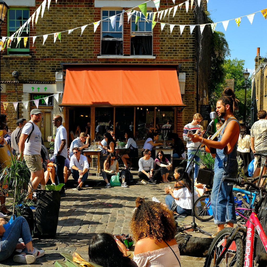 London, Great Britain: Young people having fun drinking and listening to street musicians in Hackney, East London on a sunny day