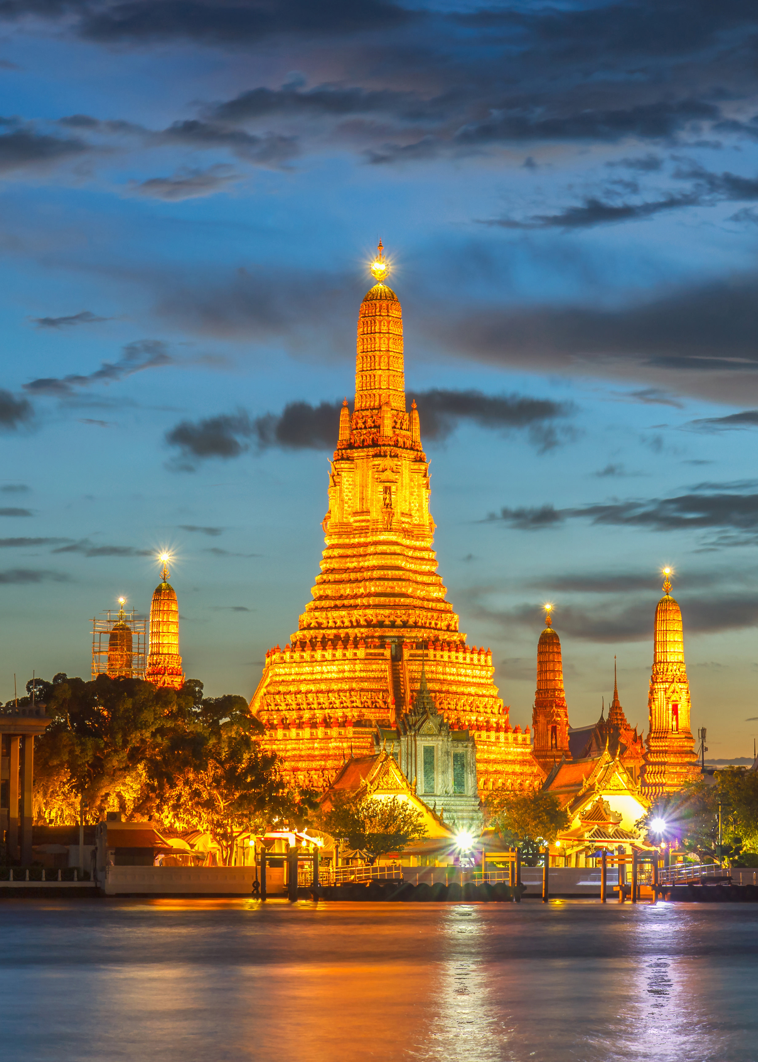 Wat Arun Buddhist temple glowing in golden light at twilight in Bangkok, Thailand. 